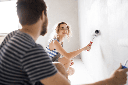 Young couple smiling and painting a wall