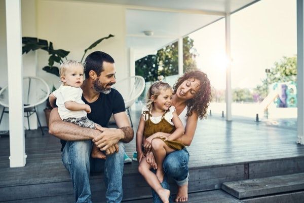 Mom, Dad & 2 young children on porch at sunset